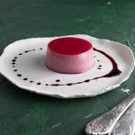 Hiniscus Panna Cotta on a plate with a drizzle of syrup and two forks on the side