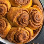 Baking dish with cinnamon rolls. Cinnamon sticks next to the dish.