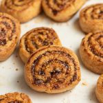 Date and walnut pinwheel cookies laying around. One cookies in the center is leaning on another facing the camera.