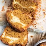 Pumpkin cream cheese bread with two slices. Glass plate with a slice on the lower right side.