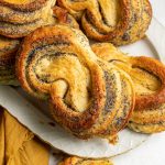 Poppy seed pastries on a plate. Yellow napkin on the side and a piece of pastry next to it.