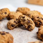 Brown butter chocolate chip oatmeal cookie broken in half, surrounded by more cookies.