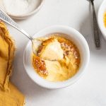 Scooping vanilla crème brûlée from a ramekin.